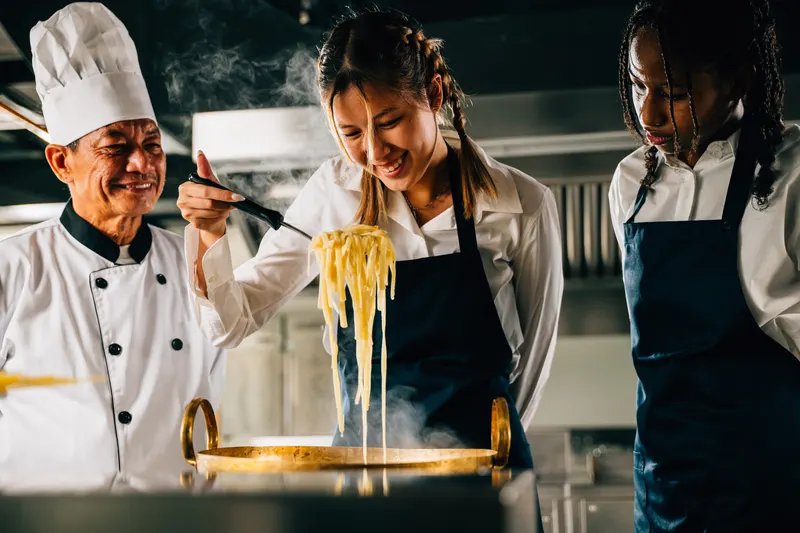 Chef teaching food handling technique in a commercial kitchen